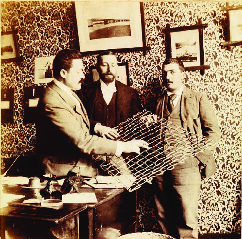 COTTANCIN, Paul. Primero a la izquierda, sosteniendo un modelo de su sistema de hormigón armado en la oficina de M.S. Reynaud (centro), en Lisboa, ca. 1904.